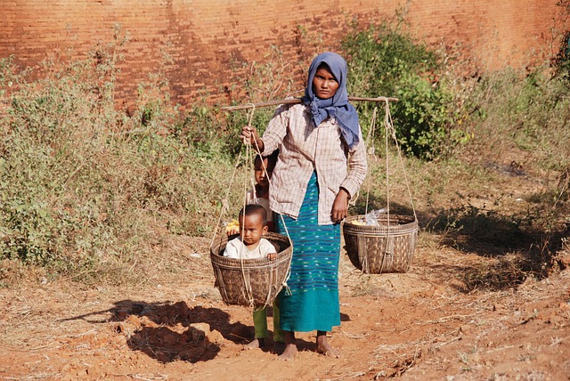 Woman carrying child in wicker basket in Myanmar